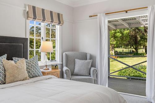 a bedroom with a bed and a chair and a window at Sutton House Southern Highlands in Moss Vale