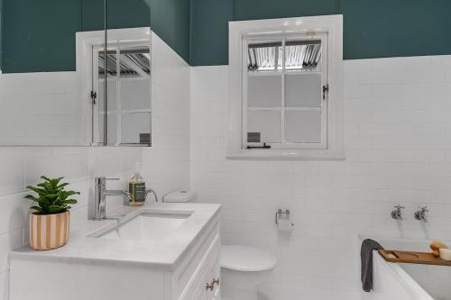 a white bathroom with a sink and a toilet at Sutton House Southern Highlands in Moss Vale