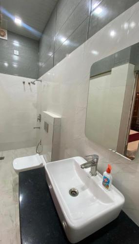 a white bathroom with a sink and a mirror at Tripathi's Rampath Inn Ayodhya in Ayodhya