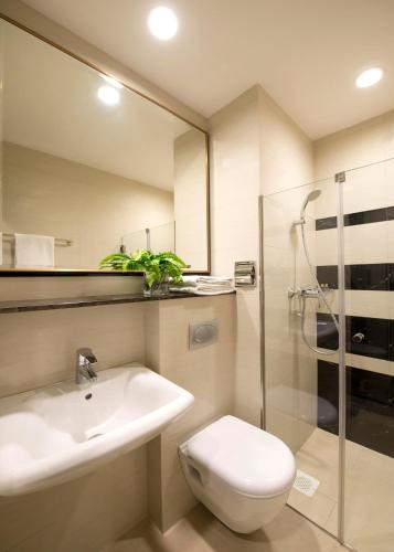 a bathroom with a sink and a toilet and a shower at V Hotel Bencoolen in Singapore