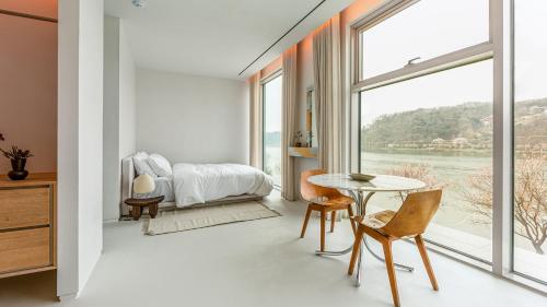 a bedroom with a bed and a table and a window at Ripple Boutique Hotel in Yangpyeong