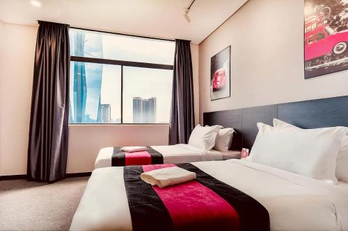 two beds in a hotel room with a window at Apex by Bukit Bintang Hotel in Kuala Lumpur