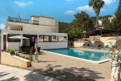 a villa with a swimming pool in front of a house at Apartments Rajsko Mjesto in Tivat