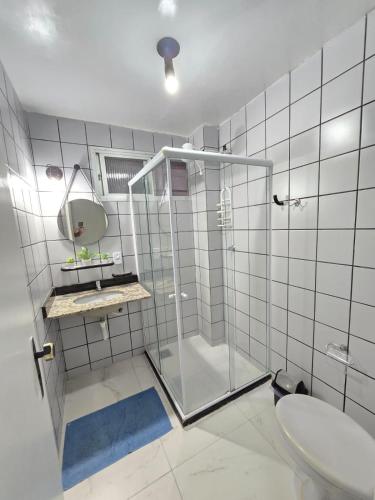 a bathroom with a glass shower and a sink at Praia Morro Katia apartamentos - Edificio Porto Belo in Guarapari