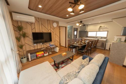 a living room with a couch and a dining room at New 充実設備&コスパ&快適重視の宿!空港美瑛富良野スキー場4ヵ所アクセス良!キッズエリア大人気 in Asahikawa