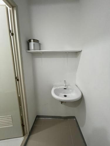a white bathroom with a sink and a shelf at Kwarto-2-Go in Pontud