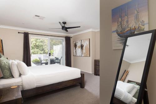 a bedroom with a white bed and a mirror at Chelsea Poolside and Tennis in Nelson Bay
