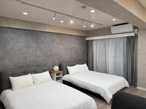 two beds in a hotel room with white sheets at ベルビー川崎 in Kawasaki