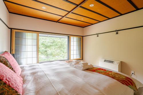 a bedroom with a large white bed with a window at Ski-in, Ski-out Iwatake Apartments in Hakuba
