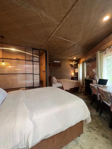 a bedroom with a bed and a desk with a laptop at Kundiman Siargao, General Luna in General Luna