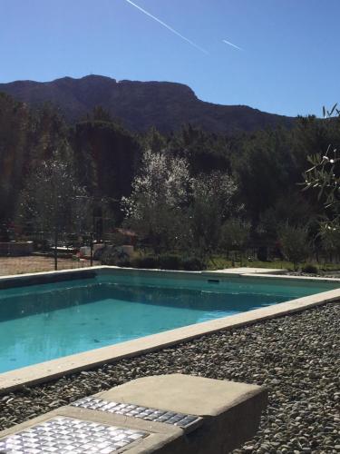 Au Havre De Paix sainte victoire vauvenargues في Vauvenargues: مسبح ازرق بجبل في الخلف