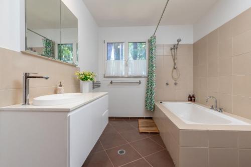 a white bathroom with a tub and a sink at The Deck in Elizabeth Beach