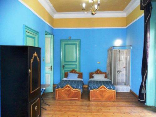 a blue room with two beds and a television at Berlin Hotel in Cairo