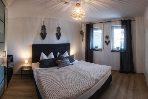a bedroom with a large bed and a chandelier at Ferienwohnung Kaiserblick in Anger