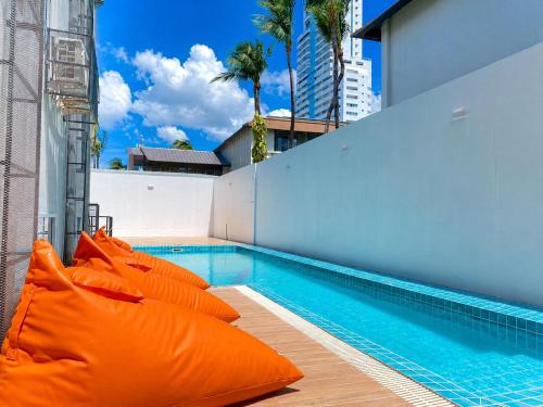 a swimming pool with orange pillows next to a building at Citin Armoni Patong Hotel by Compass Hospitality - Newly Renovated in Patong Beach