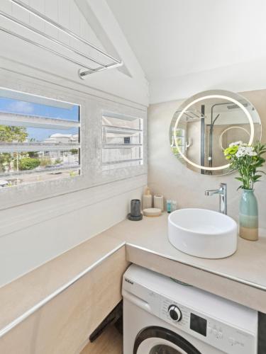 a bathroom with a sink and a washing machine at Shell Beach - Magnifique Loft sur la plage in Baie Nettle