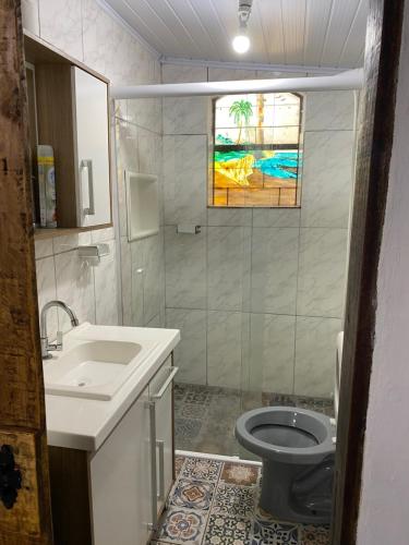 a bathroom with a sink and a toilet and a window at Sitio Piruetas in Santana do Livramento