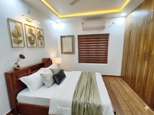 a bedroom with a bed with white sheets and pillows at Tranquil Home in Trivandrum