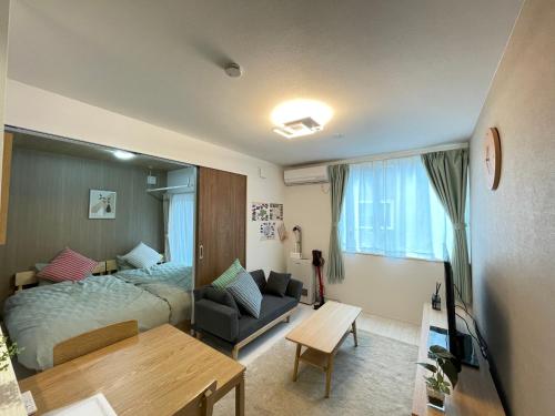 a bedroom with a bed and a couch and a table at イーエフ千歳駅 in Chitose