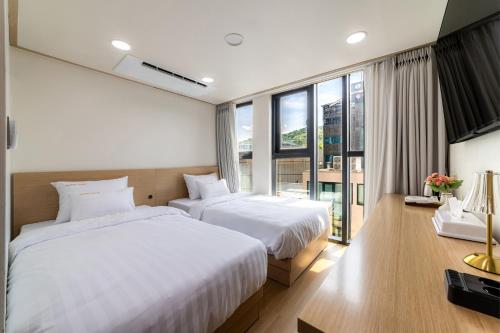 a bedroom with two beds and a large window at Bliss Hotel Myeongdong in Seoul