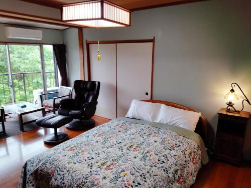 a bedroom with a bed and a chair and a window at ウテナ2 in Ito