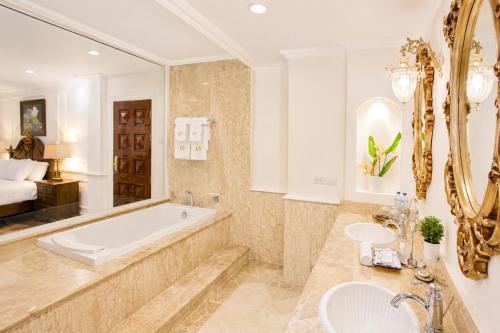 a bathroom with a tub and two sinks and a bed at Dhavara Boutique Hotel in Vientiane