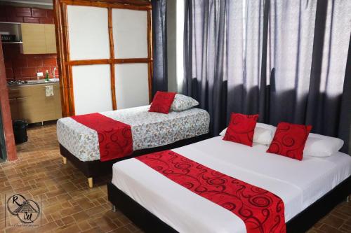 zwei Betten mit roten Kissen in einem Zimmer in der Unterkunft Rivera Maya Hotel Campestre in Rivera