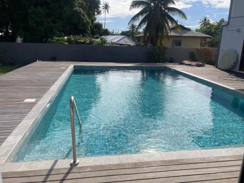 a swimming pool next to a wooden deck at Fare Zen Raiatea - with pool in Uturoa