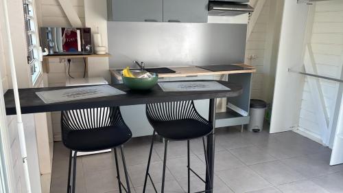 a kitchen with a counter with two bar stools at Kaz Taïnos in Baie-Mahault
