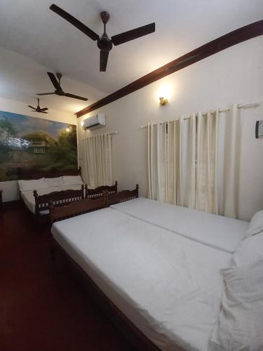 a bedroom with two beds and a ceiling fan at Taj Mahal Hotel in Cochin