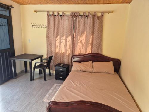 a bedroom with a bed with a desk and a window at Brisas Alojamiento in Gualanday