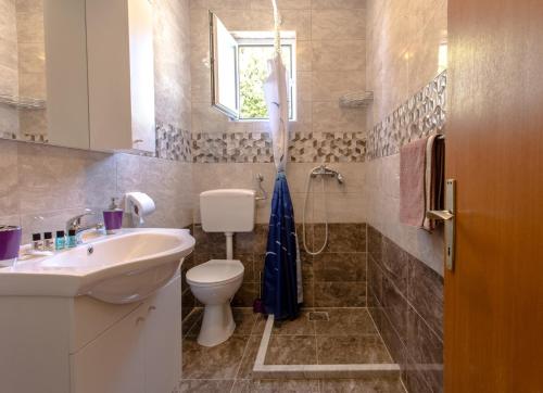 a bathroom with a sink and a toilet and a window at Apartments Dalmatia Blue in Mlini