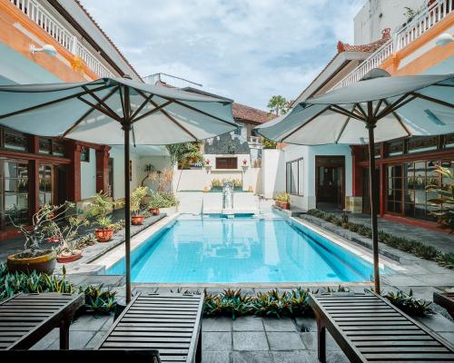 a swimming pool with two umbrellas next to a house at Natasya Kuta Beach Hotel in Kuta