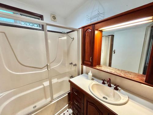 a bathroom with a sink and a tub and a mirror at Sunshine on Heath -Pet Friendly in Evans Head