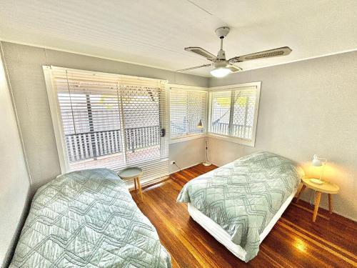 a bedroom with two beds and two windows at Sunshine on Heath -Pet Friendly in Evans Head