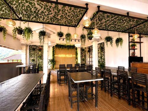 a restaurant with tables and chairs and plants on the walls at Nara Hills in Sembalun Lawang