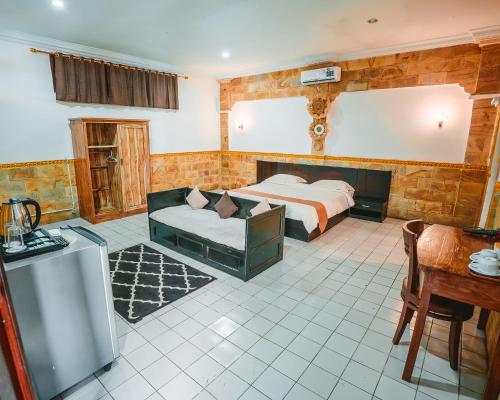 a bedroom with two beds and a couch and a table at Natasya Kuta Beach Hotel in Kuta
