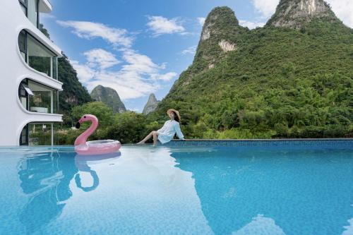 a woman sitting on a pink swan in a pool at Yulonghe Yushan Country Hotel in Yangshuo