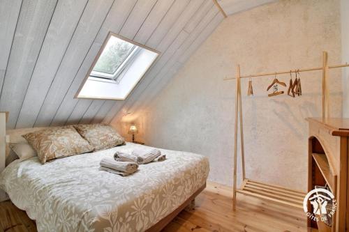 a bedroom with a bed in a attic with a window at Le refuge des oiseaux in Langonnet