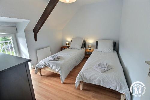 two twin beds in a room with a kitchen at Le clos rucharet in Saint-Carreuc