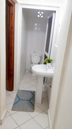 a white bathroom with a sink and a toilet at 1 bedroom apartment in shanzu near pride inn resort in Mombasa