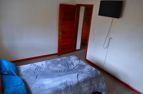 a room with a bed and a door with a television at Casa Luck Hosting in Cuenca
