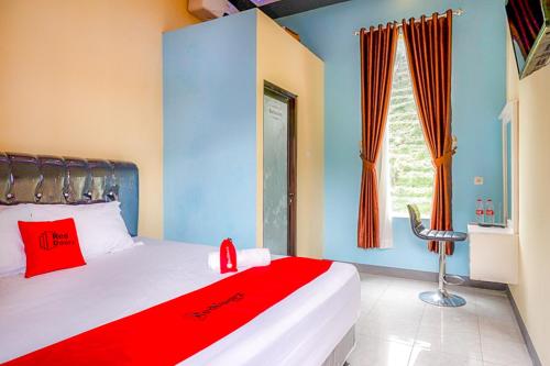 a bedroom with a bed with a red blanket and a window at RedDoorz @ Gerbang Dieng Plateau Area in Wonosobo