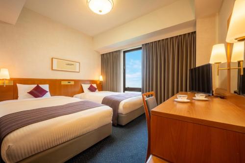 a hotel room with two beds and a desk at Iwaki Washington Hotel in Iwaki