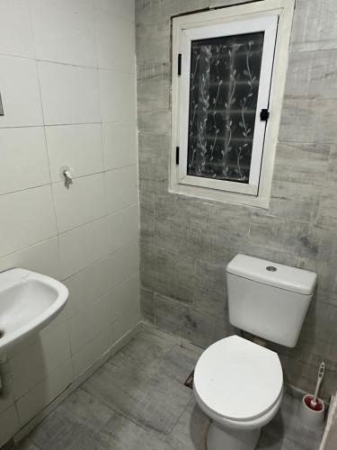 a bathroom with a toilet and a sink and a window at Quincho y hospedaje in Reconquista