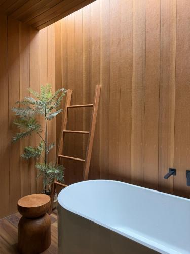 a bathroom with a bath tub and a wooden wall at Inlaya Ratchaburi in Ratchaburi