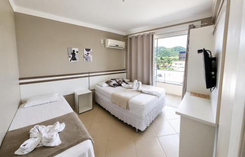 a hotel room with two beds and a balcony at Pousada Recanto do Cowboy in Penha