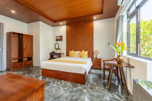 a bedroom with a king sized bed and a table at Laughter Garden villas in Tân Thành (1)