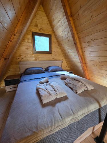 a bed in a wooden cabin with towels on it at Vila Mila in Vlaška