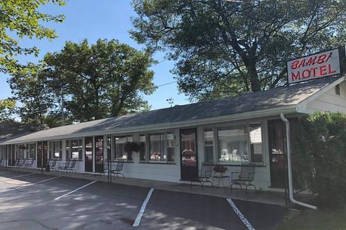 a building with chairs and a sign for a motel at Bambi Motel in East Tawas